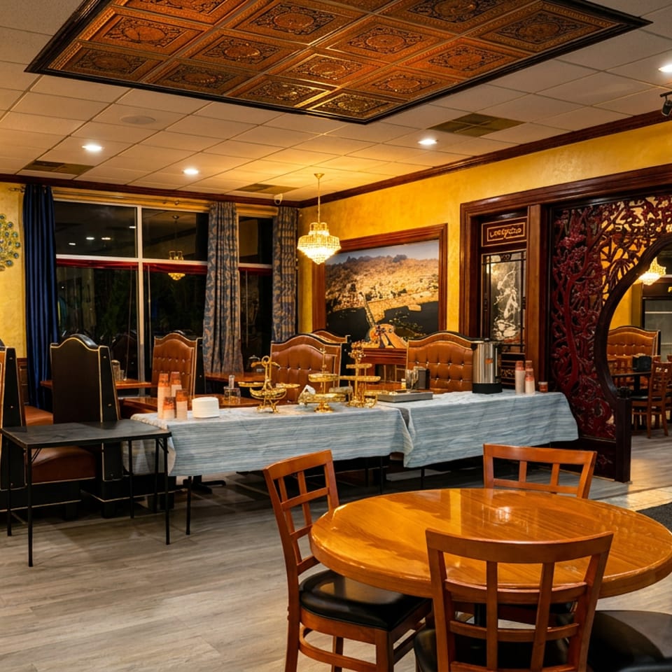 Elegant restaurant dining room with ornate woodwork, leather booths, chandeliers, round tables, and a buffet setup.